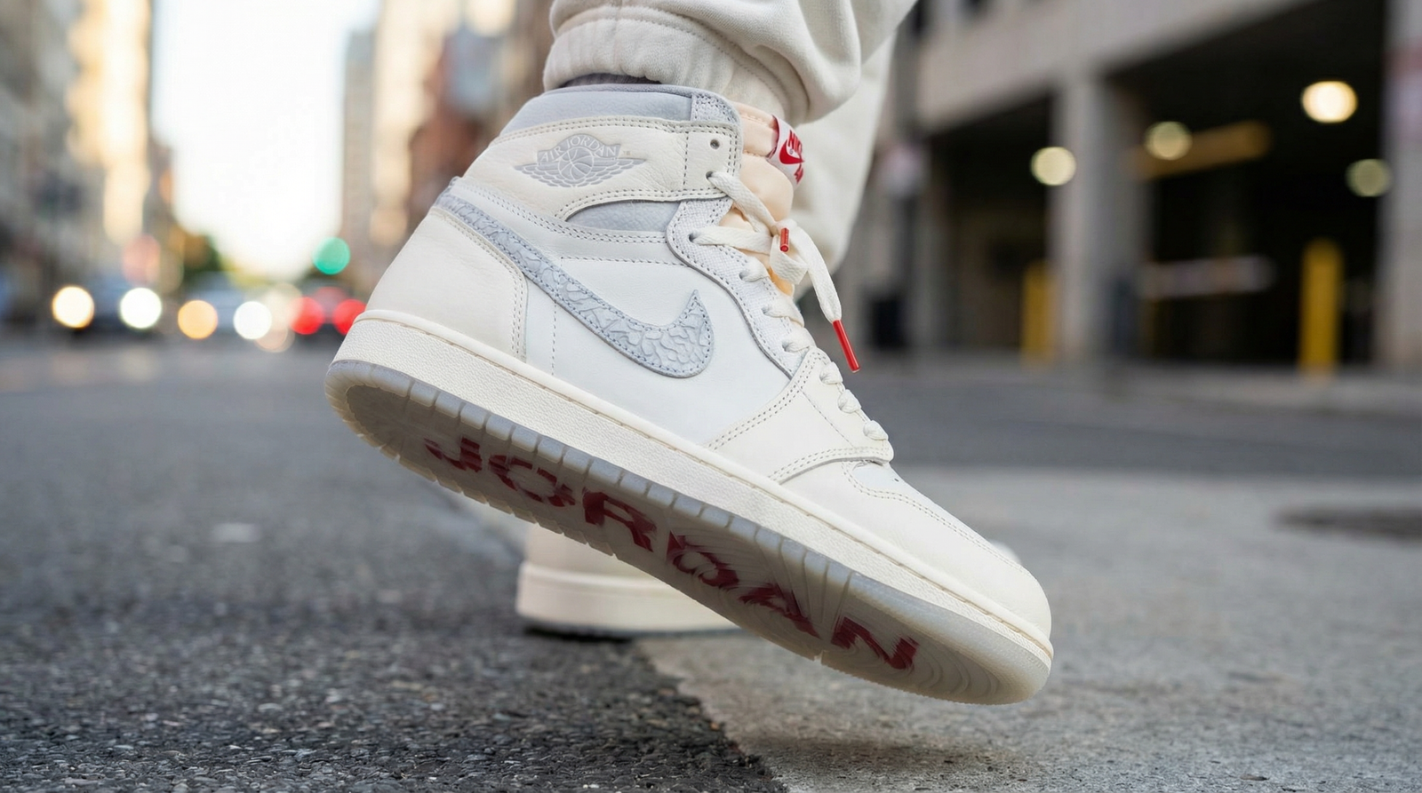 AIR JORDAN 1 High Sail University Red en gros plan sur un fond urbain flou